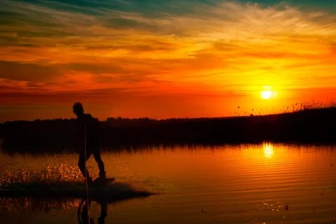 Wakeboarder making tricks on sunset Stock Photos