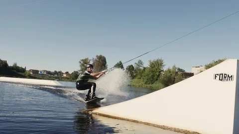 Wakeboarder man riding on string flips on ramp on lake Stock Footage 85999452