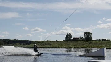 Wakeboarder man riding on string jumping on ramp on lake Stock Footage 85999441
