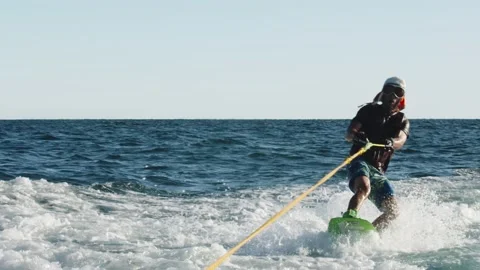 Wakeboarder man in winter cap is moving fast over the waves in the sea. person Stock Footage 201345169