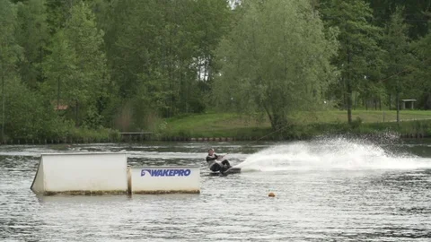 Wakeboarder performing a raley over a kicker but fails [Slomo] Stock Footage 70157967