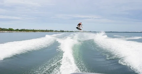 Wakeboarder performing stunts while surfing in the sea during summer Stock Footage 111422957