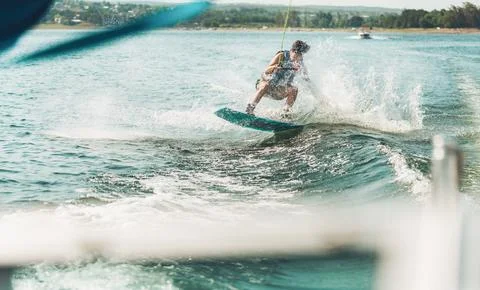 Wakeboarder riding waves creating splash on lake Stock Photos