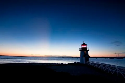 Waking light of a lighthouse at sunset Stock Photos