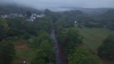 Wales, river flowing through a forest near a village. Aerial view. Stock Footage 344907604