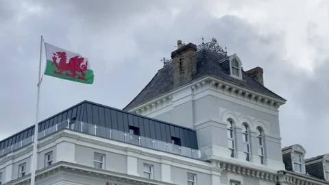 Wales Welsh flag fluttering blowing in wind old building stormy sky Stock Footage 293021964