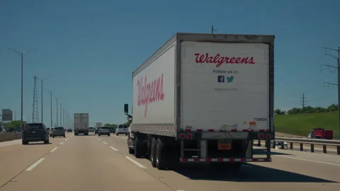 Walgreens semi truck driving on a interstate highway during a sunny day. Rear Stock Footage 340156632