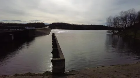 Walk along the river by the dam with views of land and water on a cloudy day Stock Footage 337125584