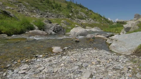 Walk along a small river lined with pebbles surrounded by mountains in Romania Stock Footage 231264489
