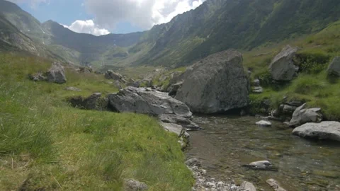 Walk along a small river lined with pebbles surrounded by mountains in Romania Stock Footage 231265495