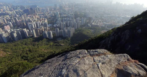 Walk to cliff edge and looking to Kowloon cityscape from Lion Rock peak Stock Footage 309437759