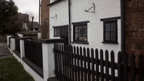Walk next to old white painted brick house with reflections in the windows. Stock Footage 87156423