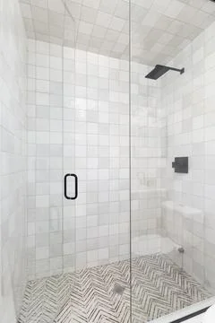 A walk-in shower with square and pattern tiles. Stock Photos