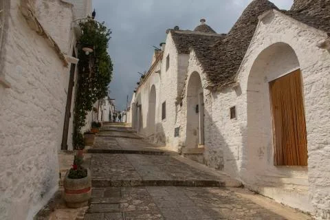 Walk uphill on empty narrow path in Alberobello peaceful trulli town Stock Photos