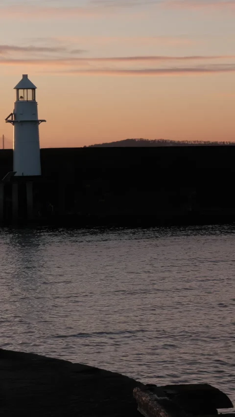 Walk by the water as the sun sets over, Burntisland West Pier Lighthouse and Stock Footage 302518918