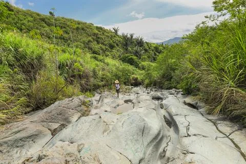 Walker on an old lava flow, now a smooth eroded river bed and hiking trail to 스톡 사진