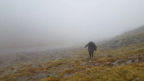 Walker struggling in the wind, rain and fog in the Lake District, England Video stock 105277730