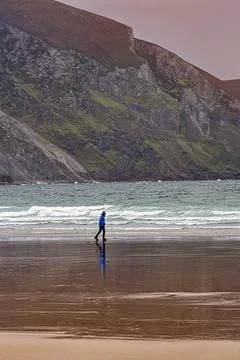 Walker walking along the beach in the evening Keel beach Acaill Achill Island Foto stock