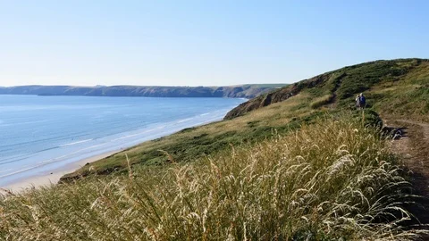 Walkers on the coast path over looking Newgale and St Brides Bay Stock Footage 93175872