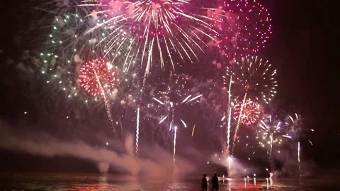 Walkers walking on the beach during a firework over the sea Video stock 91697322