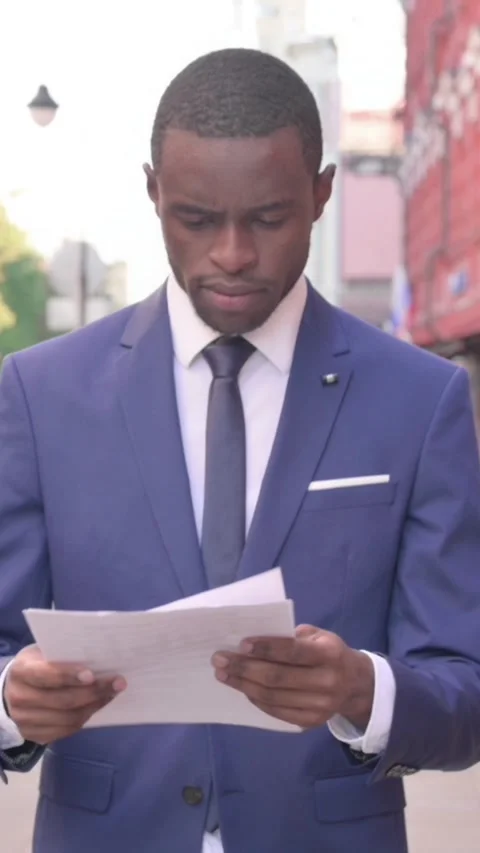 Walking African Businessman Reading Documents, Vertical Video Stock Footage 340031331