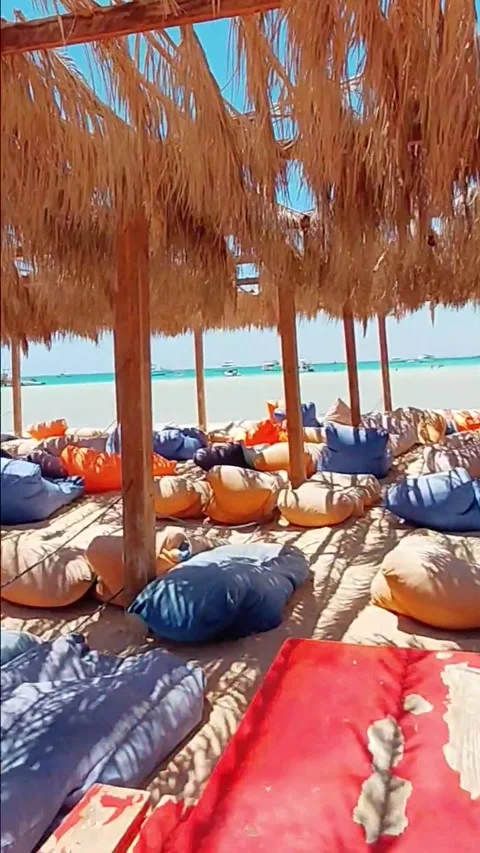 Walking along beach under straw canopy at Orange Bay island Hurghada Egypt Stock Footage 341358223