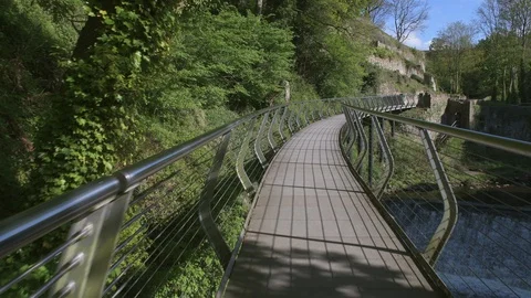 Walking along the Millennium Bridge, a raised footbridge above the River Goyt Stock Footage