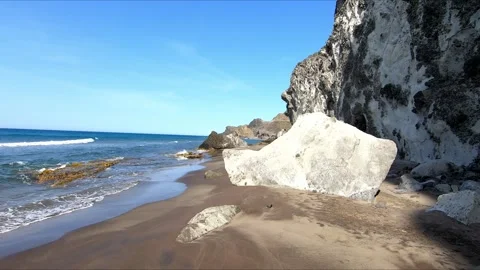 Walking along a narrow sandy beach under a cliff Stock Footage 268901448