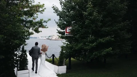 Walking along the pier. The bride and groom are walking along the pier to the ri Stock Footage 129463756