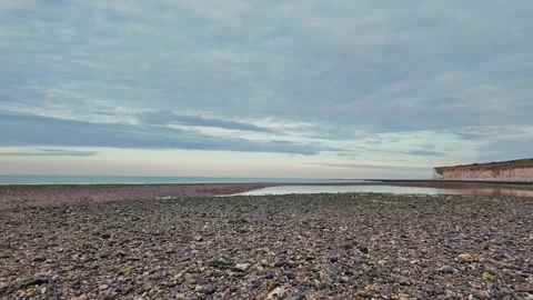 Walking along quiet pebble beach with sea groynes and coastal cliffs Stock Footage 309767446
