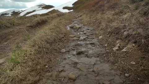 Walking along a rocky path with flowing water in a mountainous area Video stock 327139277