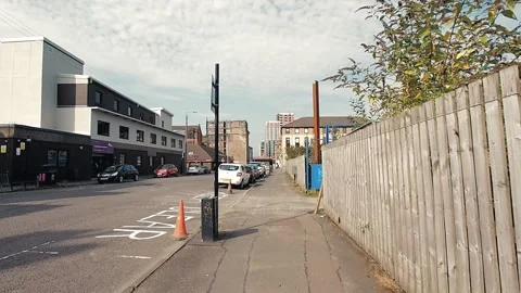Walking along a sidewalk leading to a set of blue gates. Video stock 160437317