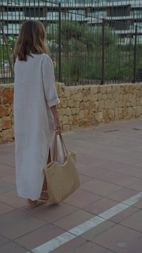 Walking along a stone pathway with a bag in hand in a sunny location Stock Footage 342786605