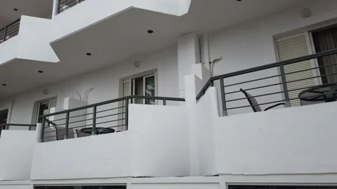 Walking along the wall of a white building of a Greek hotel. Video stock 154395952