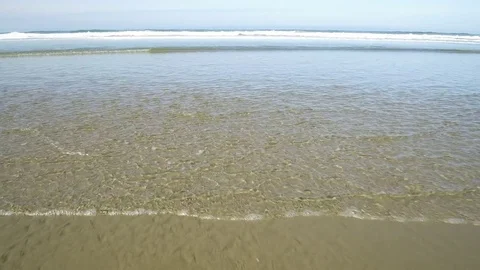 Walking away from the ocean edge on a sand beach coast Stock Footage 84265972