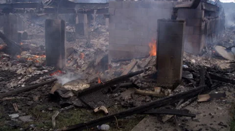 Walking back and forth past concrete foundation pillars amid flaming debris in Stock Footage 59515199