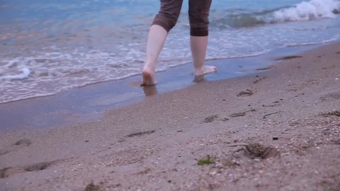 Walking barefoot along the surf on the sand beach at sunset close up. Legs of a Stock Footage 92753461
