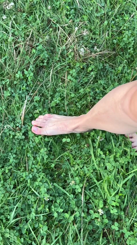 Walking barefoot by wet grass Stock Footage 253982604