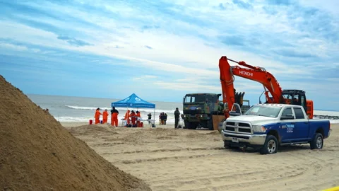 Walking by the beach behind the yellow caution tape. People and machines work at Video stock 333412870