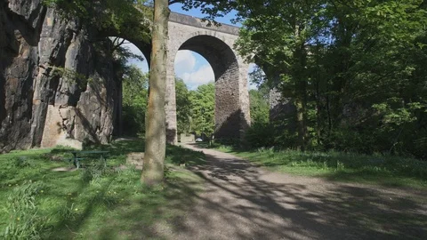 Walking below a tall, stone, arched bridge 動画素材 129577007