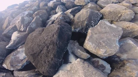 Walking on big boulder pill of rocks at coastline protection from lagoon atoll o Stock Footage 258443949