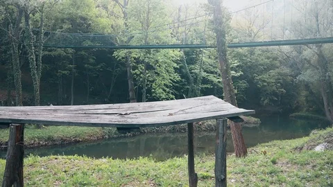A walking bridge across the river in the mountain. The old wooden desk in front Vídeo Stock 109094011