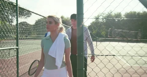 Walking coach and two players after practice stepping through gate retrieving Stock Footage 335069569