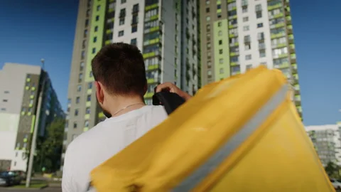 A walking courier throws a yellow bag on his shoulder Stock Footage 205440623