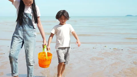 Walking cute boy playing water and sand outside on the beach together Видео 199264855