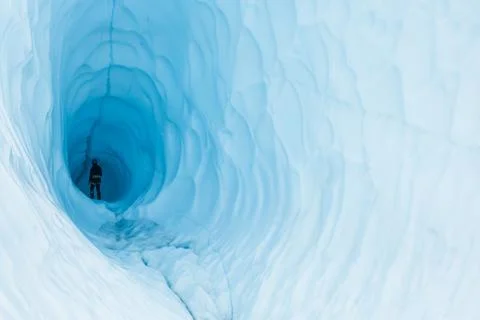 Walking into the darkness of a deep and dark ice cave on the Matanuska Glacie Stock Photos