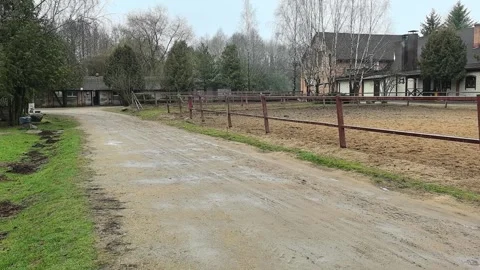 Walking on a dirt path near a stable area in early spring by an empty horse ridi Stock Footage 330154934