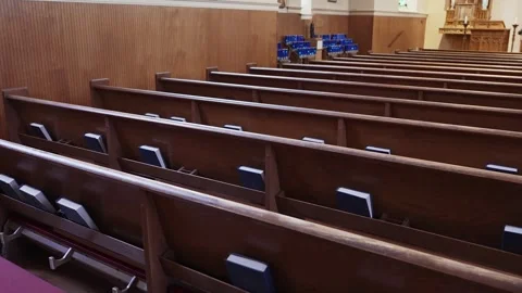 Walking down aisles of a church looking at Bibles, candles, and wooden church pe Video stock 324773465