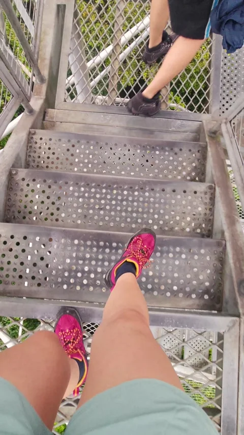 Walking down metal grating stair treads wearing shorts and hiking boots Stock Footage 309121809