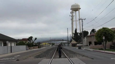 Walking down railroad tracks with water tower in background Stock Footage 155489416